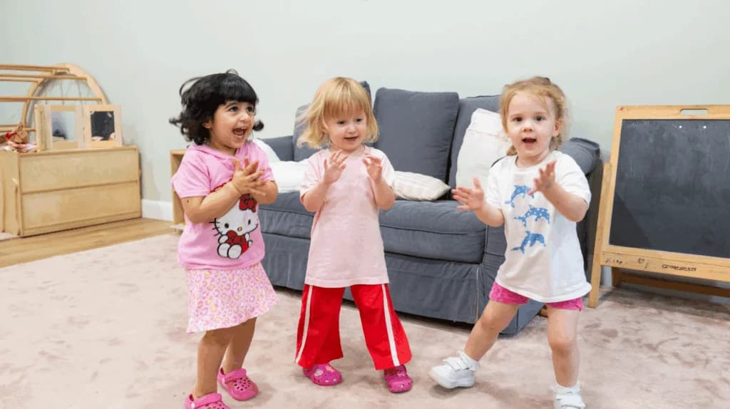 Three toddlers dancing and clapping together during music and movement at Simba Education