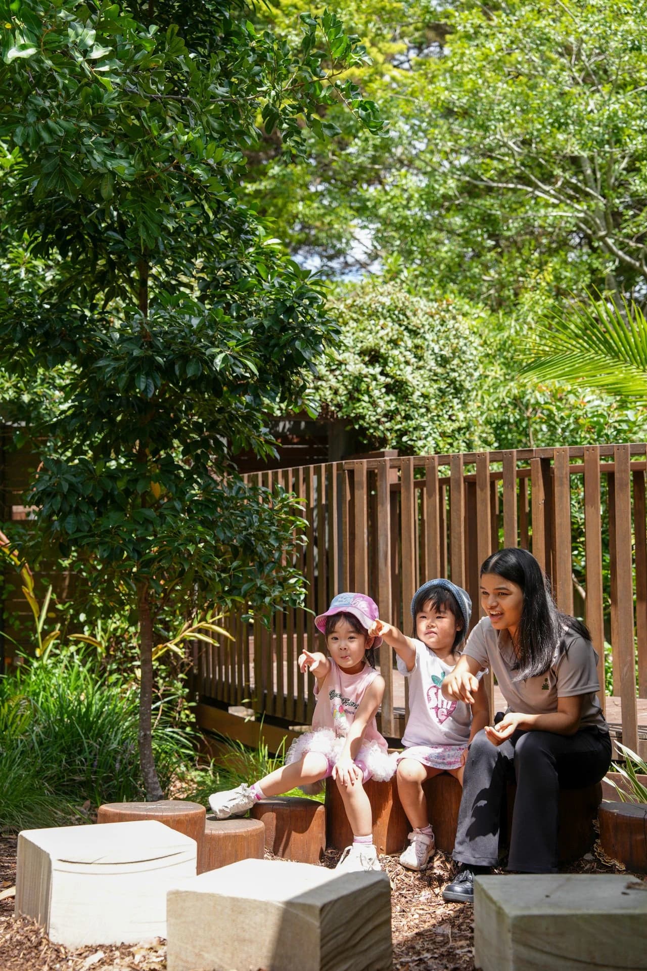 An educator sitting with children in an outdoor learning environment